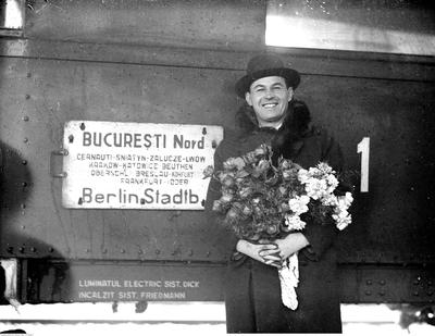 Jan Kiepura z bukietem kwiatów stoi przed pociągiem na chwilę przed odjazdem, 1935 rok © Narodowe Archiwum Cyfrowe (sygnatura: 1-K-8238-9)