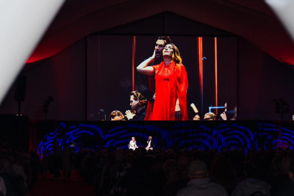 Roman Osadnik i Robert Kamyk. Spotkanie przed projekcją „Carmen” na Ogrodach Muzycznych. Na ekranie Sonya Yoncheva i Jonathan Tetelman podczas koncertowego wykonania „Toski” na Centralnym Placu Muzyki © Piotr Łabanow